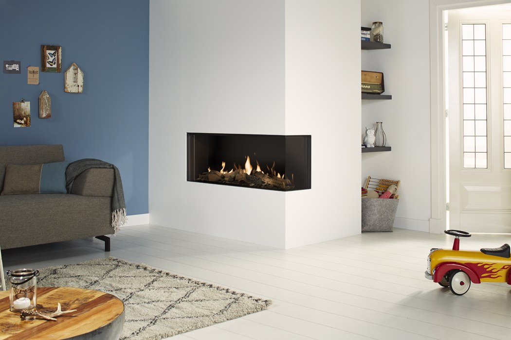 Șemineu pe gaz DRU Global 100 Corner BF, varianta dreapta (geam lateral în dreapta), încastrat în colțul unui coș fals alb, interior negru și lemne maro